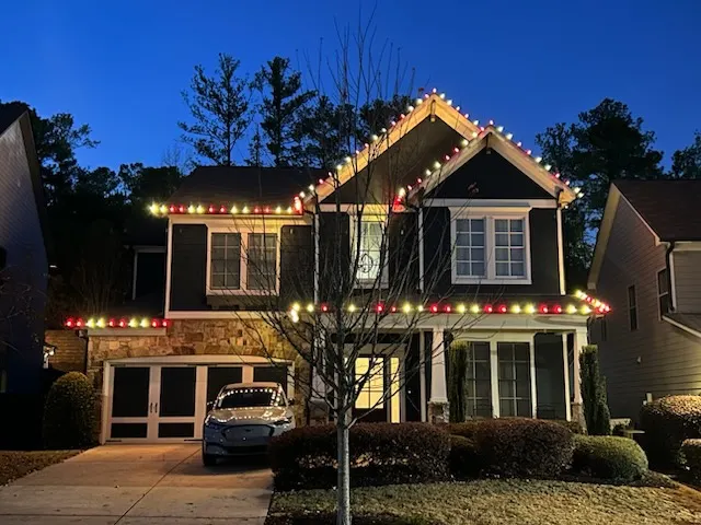 Red, green, and warm white Christmas lights decorating a residential roofline and exterior in Cumming, Georgia.