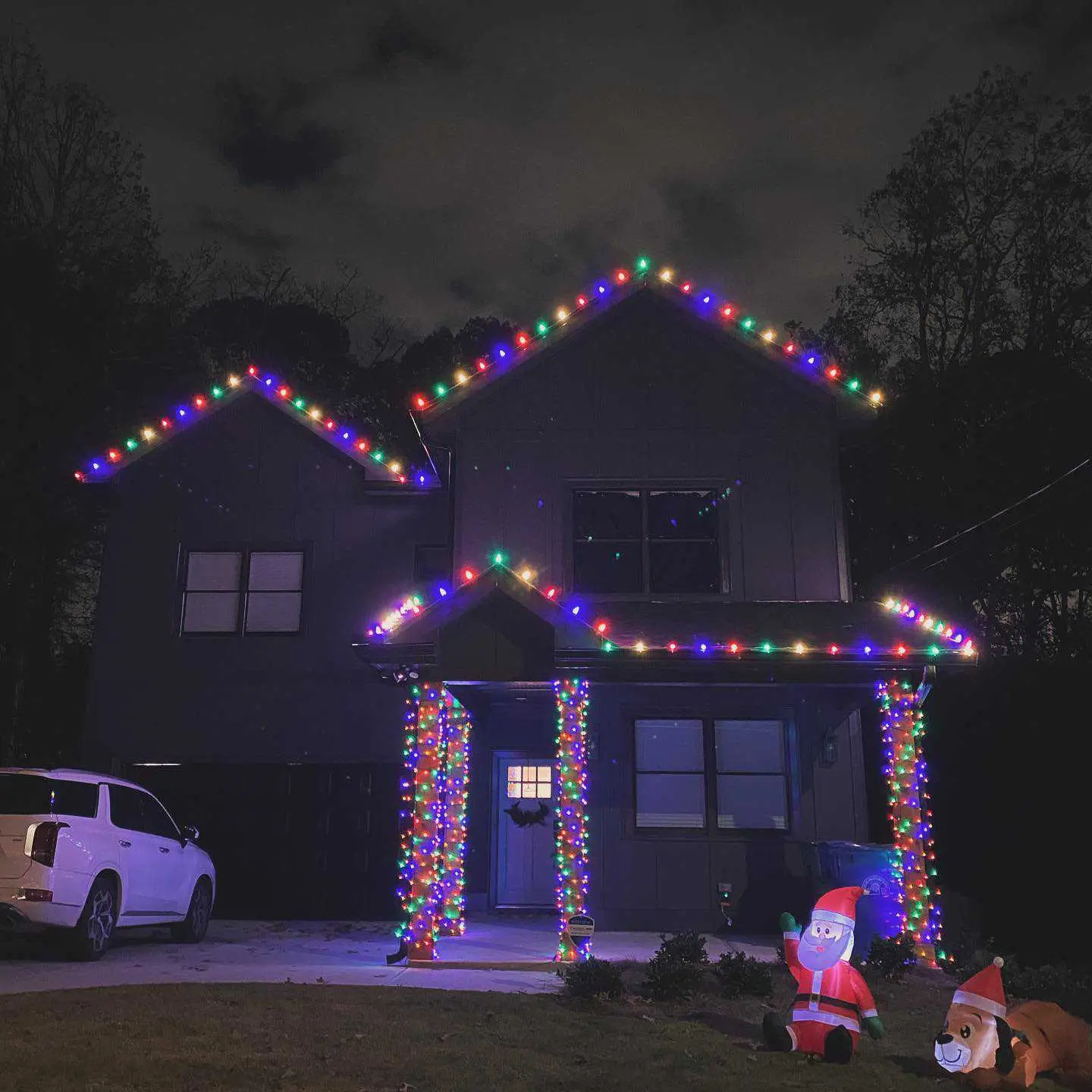 Multicolor Christmas lights decorating a two-story home with roofline and exterior accents in Cumming, Georgia.