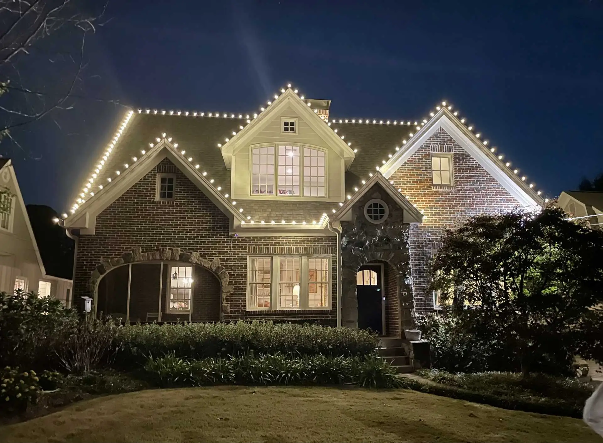 Warm white professional Christmas lights outlining multiple rooflines on a residence in Cumming, Georgia.