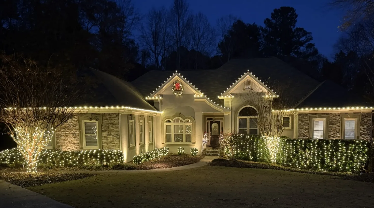 Warm white roofline and landscape Christmas lights illuminating a residence in Cumming, Georgia.
