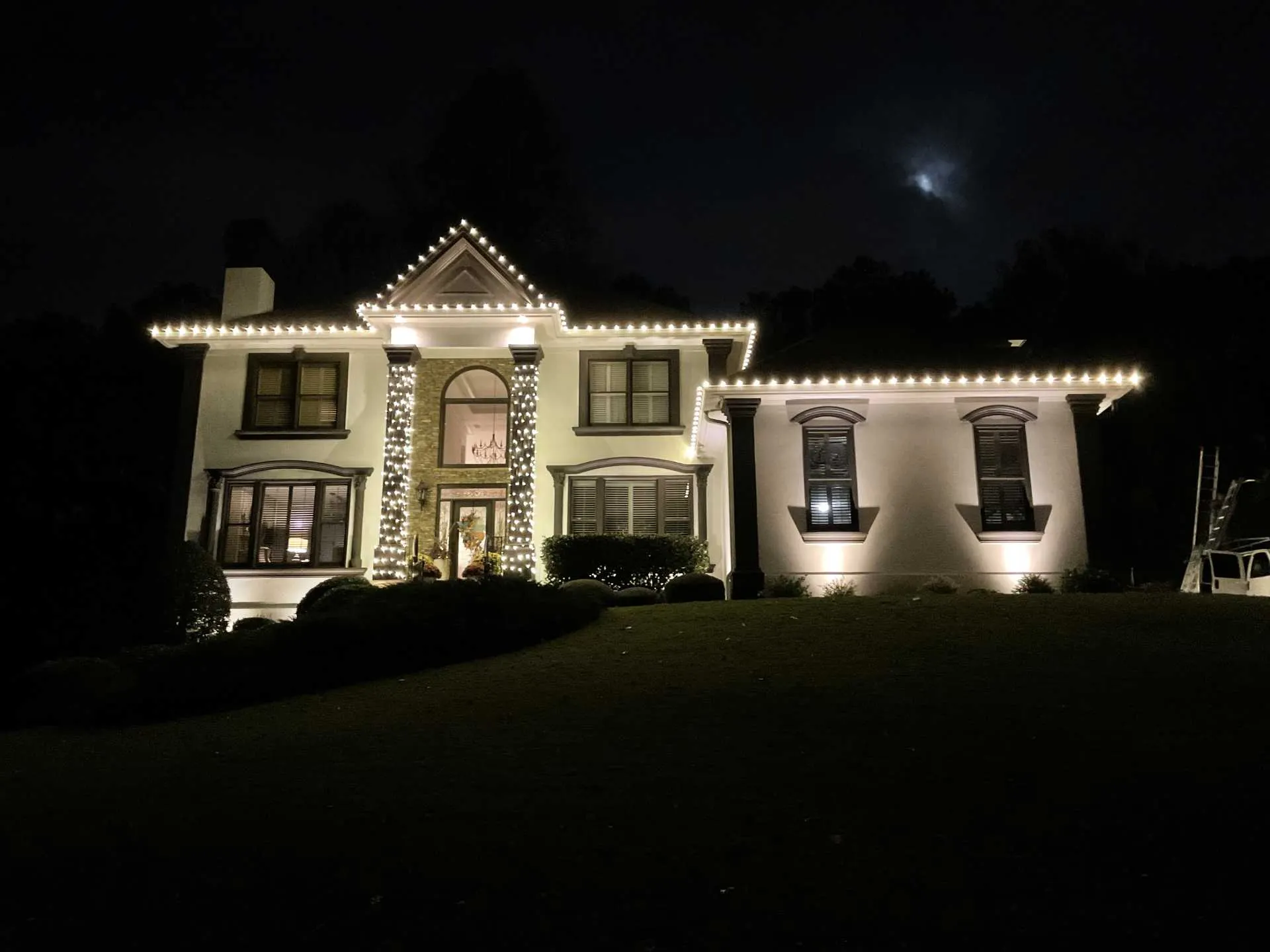 Warm white Christmas lights installed along the roofline and exterior of a large home in Cumming, Georgia.